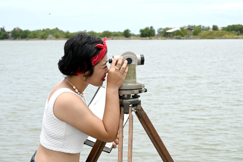 Pretty Asian female surveyor or engineer worker working with theodolite transit equipment at outdoor construction site .