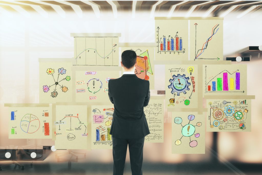 Man looking to the business graphs on the glass window in a modern office