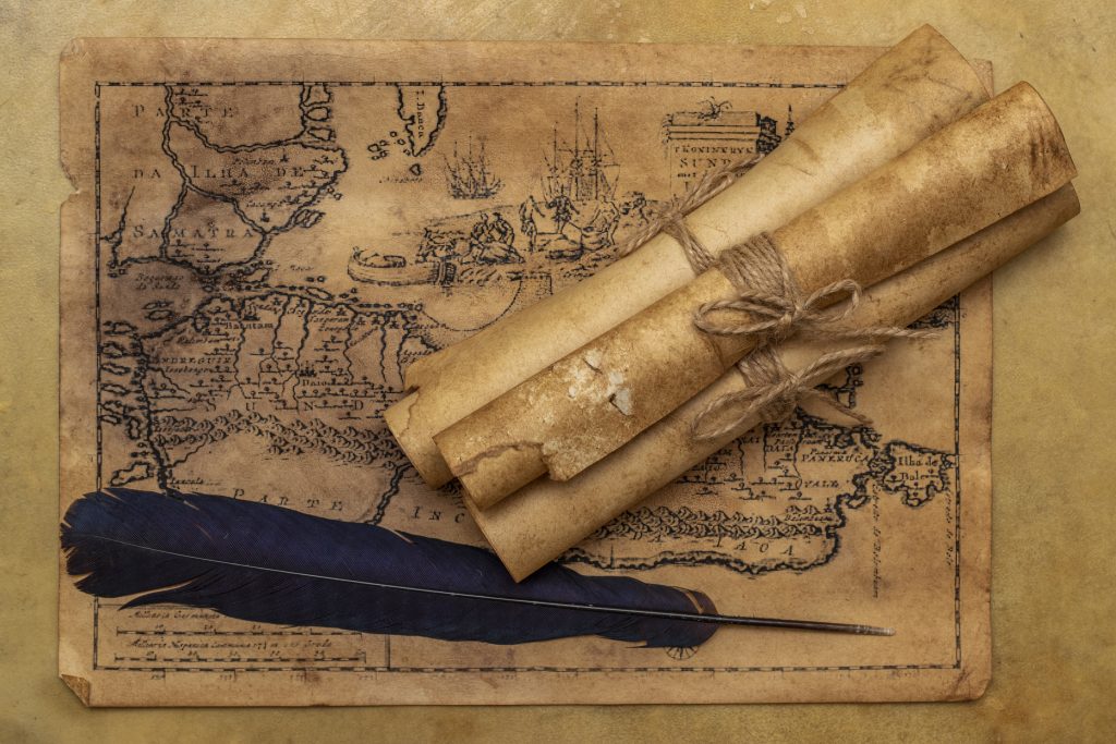 Old map, paper scrolls, raven feather for writing. Vintage image.