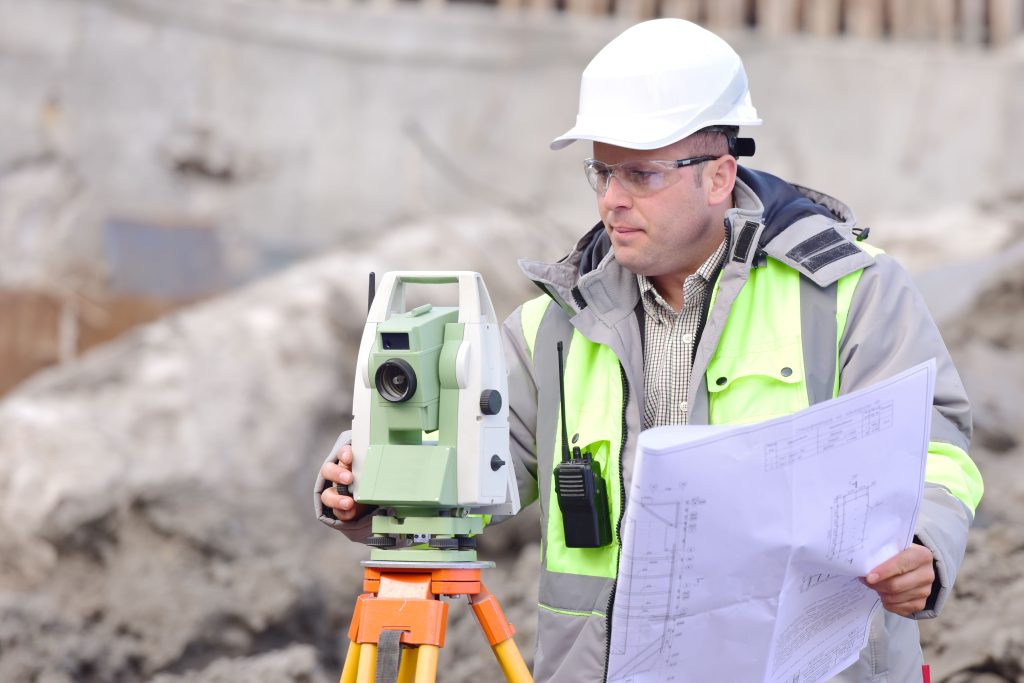 Surveyor at at construction site is inspecting ongoing production according to design drawings.
